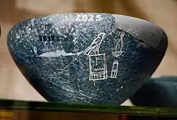 Speckled dark grey stone bowl, a small section of which is inscribed with light-coloured hieroglyphs
