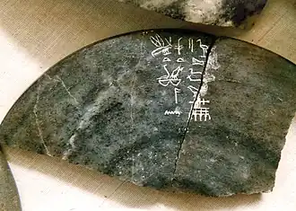 Fragment of a dark-grey stone bowl inscribed with light-colored hieroglyphs
