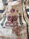 Parochet with the emblem of the State of Israel, Menorah, and olive tree branches with leaves.
