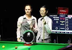 Two women standing at a snooker table