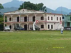A two story tall white building with a large grass area in front