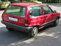 Rear-three-quarter view of a small three-door car with a flat roof, black-plastic bumpers, door mirrors, a sunroof, and hubcaps.