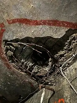 The picture shows the ceiling of a tunnel inside Fort d'Aubin-Neufchâteau. The concrete and steel shown at the ceiling is completely bent.