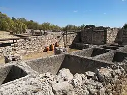 The picture depicts fish-processing tanks in stone from the Roman period. Walls of buildings can also be seen in the background.