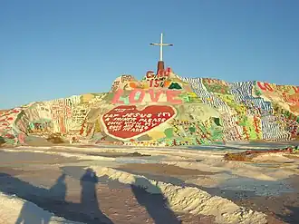 Colorful painted hillside artwork with "God is Love" message and religious imagery