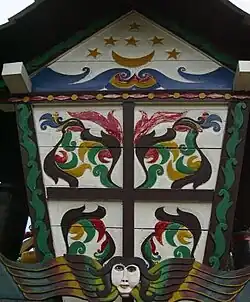 Side of a Sandung filled with paintings of crescent moon, stars, and celestial spirit with two wings