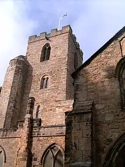 A stone church building with a tower. On the top of the tower, a Saltire flag flies on a pole.