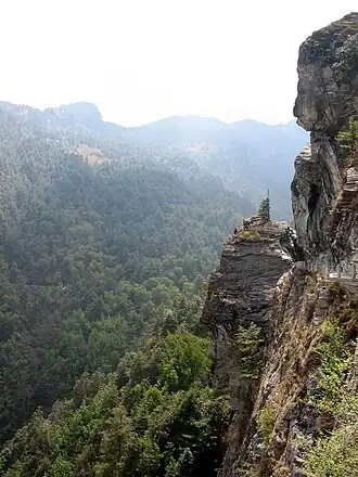 Steep cliffs overlooking hills covered in forest