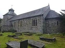 View of the south wall of the church and the apse, with gravestones in the foreground.