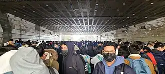 Hundreds of students crowding under a bridge due to a bomb threat.