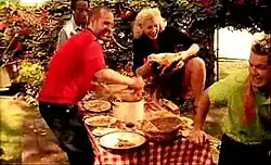 A still from the music video showing band members in a backyard food fight scene with flying food and casual clothing.