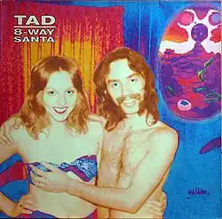 A couple in swimsuits posing for a photo, with the man groping the woman's breast
