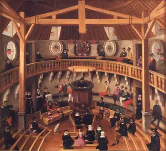 The interior of a church with a minister in the pulpit before a congregation with a woman holding a pitcher and a man with a towel next to the pulpit.