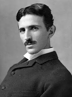 Head-and-shoulder photograph of a slender man with dark hair and moustache, dark suit and white-collar shirt