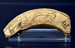 Sherd. The exterior is painted with a design; lustrous black paint on apricot-coloured clay with a burnished surface. The design of spotted animals possibly represents leopards