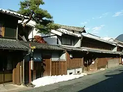 Two storied traditional Japanese houses next to a street.