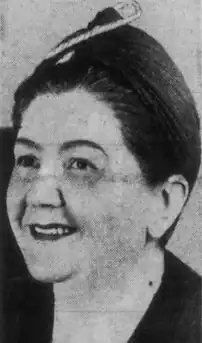 A middle-aged smiling white woman with dark hair in an updo