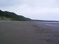 Photograph of the wide sandy beach with hills behind it