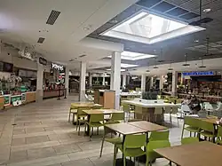 The Willowbrook Mall food court in 2024, with square skylight. Franchises visible include Carvel, Cinnabon, Popeyes, Charleys Cheesesteaks, and Wetzel's Pretzels.