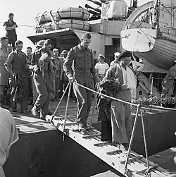 A black and white photograph showing wounded British soldiers disembarking from a warship
