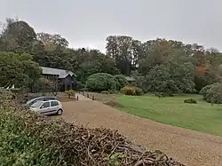 The entrance to a restaurant with trees in the background and cars in front.