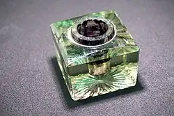 Чернильница. Конец XIX — начало XX вв. Описание: форма куба,  сверху цилиндрическое отверстие для чернил, бока гладкие, низ — лучи от центра. Размеры: 4х4х4 см.  Материал, техника: стекло, фабричное производство, штамповка.