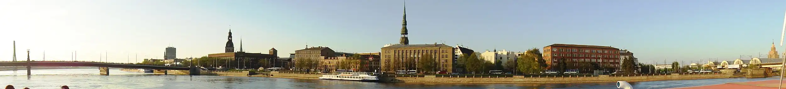 Набережная 11 Ноября. Слева — Каменный мост через Даугаву, правее него шпили Домского собора и церкви Св. Екаба. Здание в центре — Государственная земельная служба Латвии, за ней — шпиль церкви Св. Петра. Справа — Центральный рынок и здание Академии наук Латвии