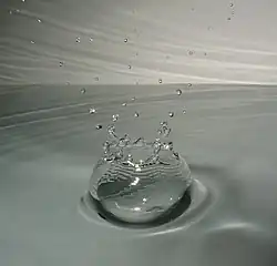 Капля, ударяющаяся о поверхность воды.