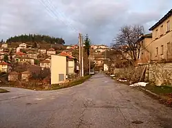 Деревенская улица в селе Скобелево с домами по обе стороны, холмы на заднем плане.