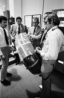 Слева направо: Джон Янг, Чарли Дьюк (оба ещё с усами), Дональд Слейтон и другие сотрудники НАСА в ЦУПе обдумывают способы ремонта крыла «Ровера»