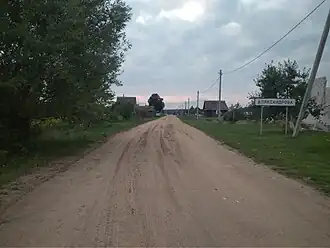Въезд в Александрово со стороны Даниловичей. На въездном дорожном знаке можно заметить орфографическую ошибку («Аляксандро́ва» вместо «Александро́ва»)