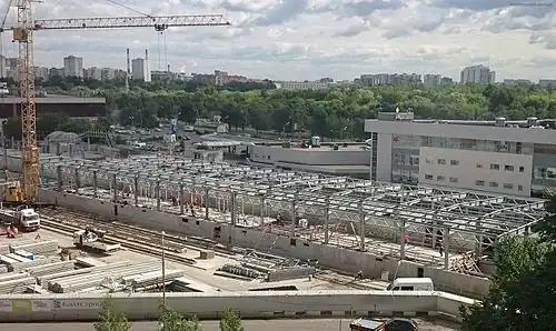 Июнь 2015 года. Сооружение крыши станции. Между платформами виден временный защитный навес, в котором следуют поезда