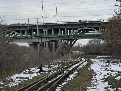 Узкоколейный путь, проходящий под мостом через реку Царица
