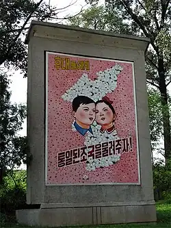 Плакат северокорейской пропаганды, гласящий: "Давайте перейдем к единой стране к следующему поколению!".