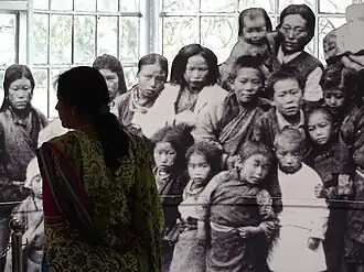 Посетительница Тибетского музея перед фотографией тибетских детей