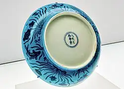 Цзиндэчжэньская тарелка с сине-белым рисунком под бирюзовой глазурью с лотосов и рыб. Эпоха правления Чэнхуа, восьмого императора из династии Мин (1465–1487). Восточный филиал Шанхайского музея.