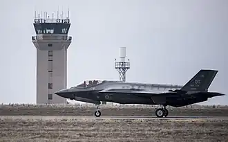 F-35A Lightning II из состава 366-го истребительного авиаполка[англ.] осуществляет посадку. Виден командно-диспетчерский пункт