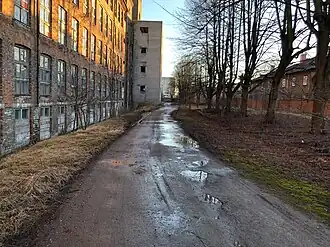 Часть улицы между заброшенным фабричным корпусом и домами на улице Ситси, март 2019 года