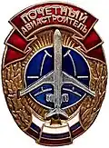 Нагрудный знак «Почётный авиастроитель Российской Федерации» (вариант 1990-х годов с красной лентой вверху, лентой цветов российского флага внизу, силуэтом самолёта Ил-62 и винтовой закруткой)