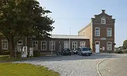 Старинный дом в деревне, перед которым установлен монумент жителям, погибшим в Первой и Второй мировых войнах.