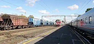 Два одноимённых пассажирских поезда противоположных направлений, Новороссийск-Москва (справа) и Москва-Новороссийск (в центре), встретились на станции Усмань. Слева — составы из вагонов для перевозки зерна (продукции сельскохозяйственной отрасли Липецкой области).