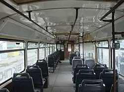 Салон трёхдверного вагона Tatra T3D компоновки 1+2 с сиденьями изменённой конструкции и площадкой без сидений напротив средней двери, вид вперёд