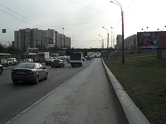 Вид со стороны Купчино: на переднем плане железнодорожный путепровод, за ним — автомобильный (перед ними — мост через канал)