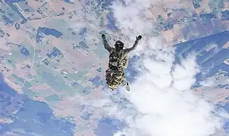 Оперативник службы выполняет прыжок с парашютом на большой высоте.