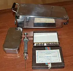 Стеклянный многоразовый шприц типа «Рекорд» с несъёмным металлическим наконечником металлическим поршнем, многоразовые иглы и наплитные кипятильники применявшиеся для стерилизации кипячением